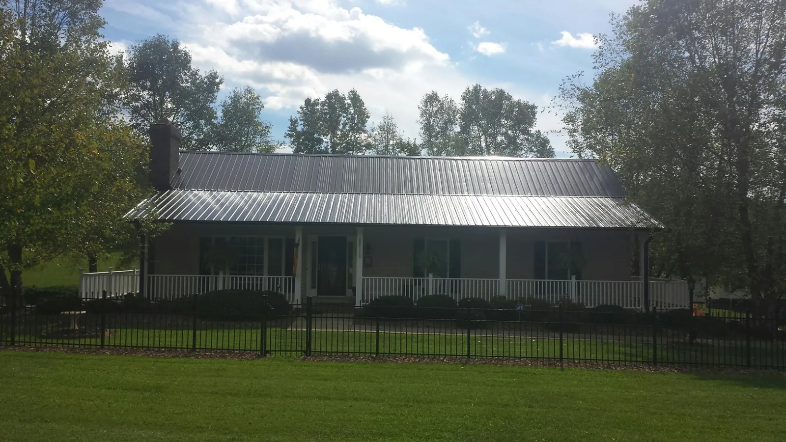 Gray metal roof on a brick ranch with a full width front porch — Gutter Guard Installation work by our crew in Pine